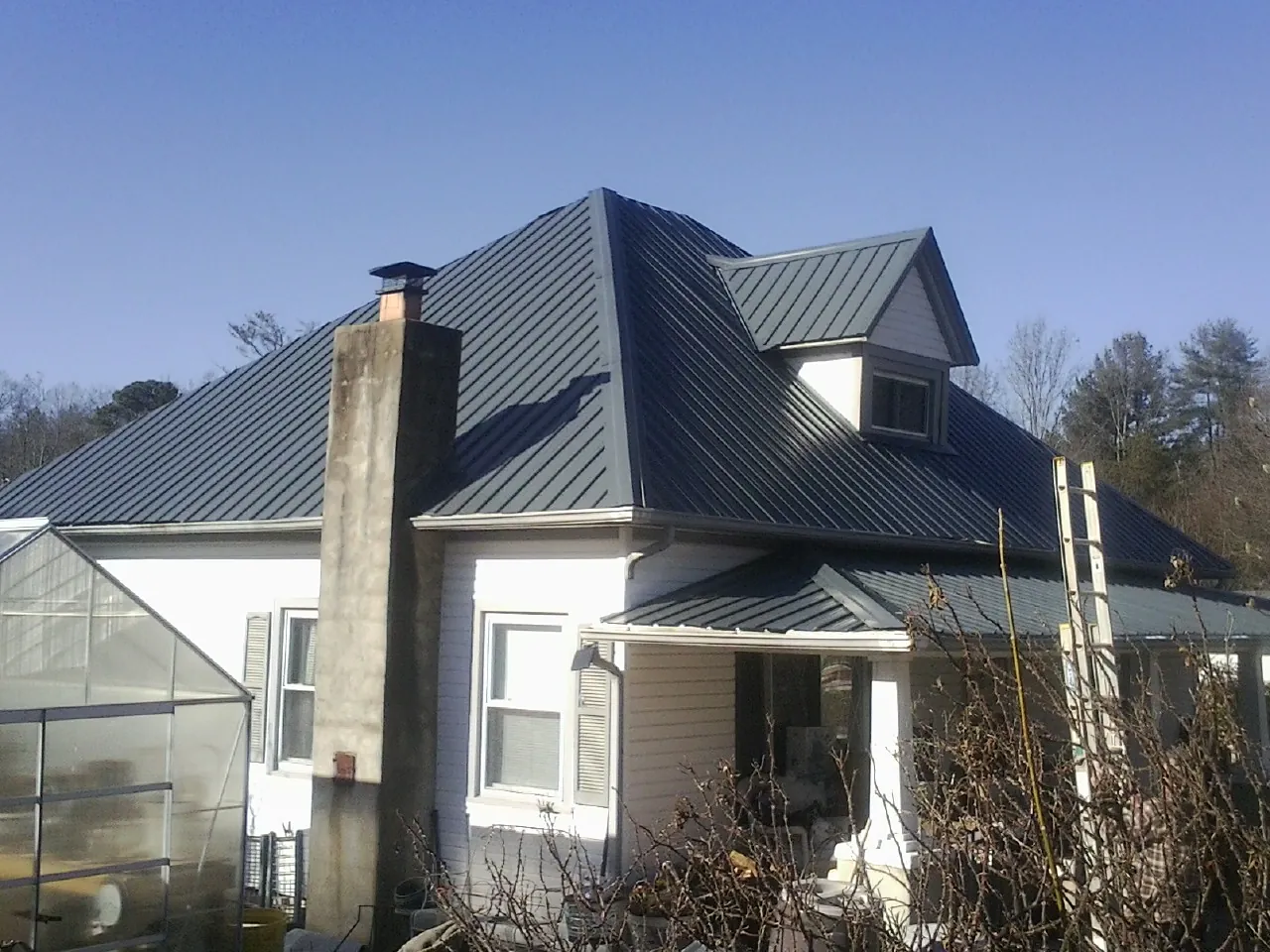 Dark blue standing seam metal roof on a white farmhouse with dormer — Slate & Tile Roof Repair by Roofing Brothers in Indian Mound