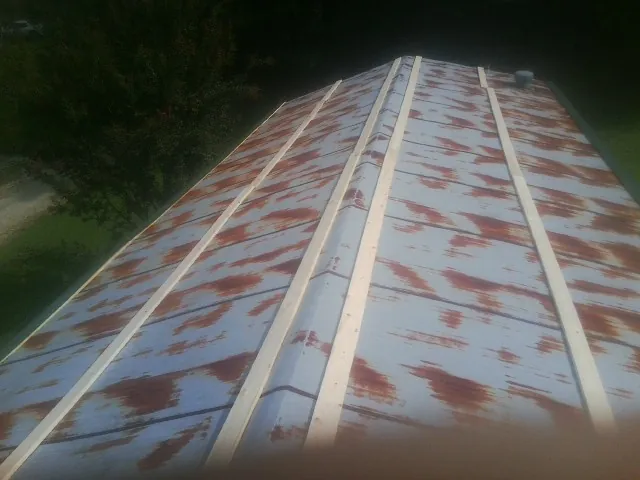 Rusted metal roof panels with new wood purlins before replacement — Storm Damage Roof Repair in Indian Mound by Roofing Brothers