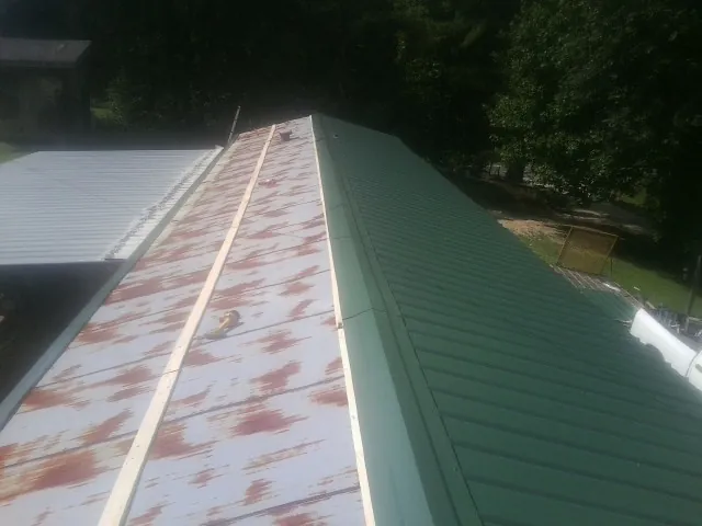 Old rusted panels beside newly installed green metal roofing — Wind Damage Roof Repair by Roofing Brothers in Indian Mound