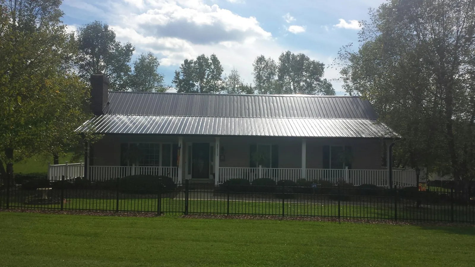 Gray metal roof on a brick ranch with a full width front porch — Gutter Guard Installation work by our crew in Indian Mound