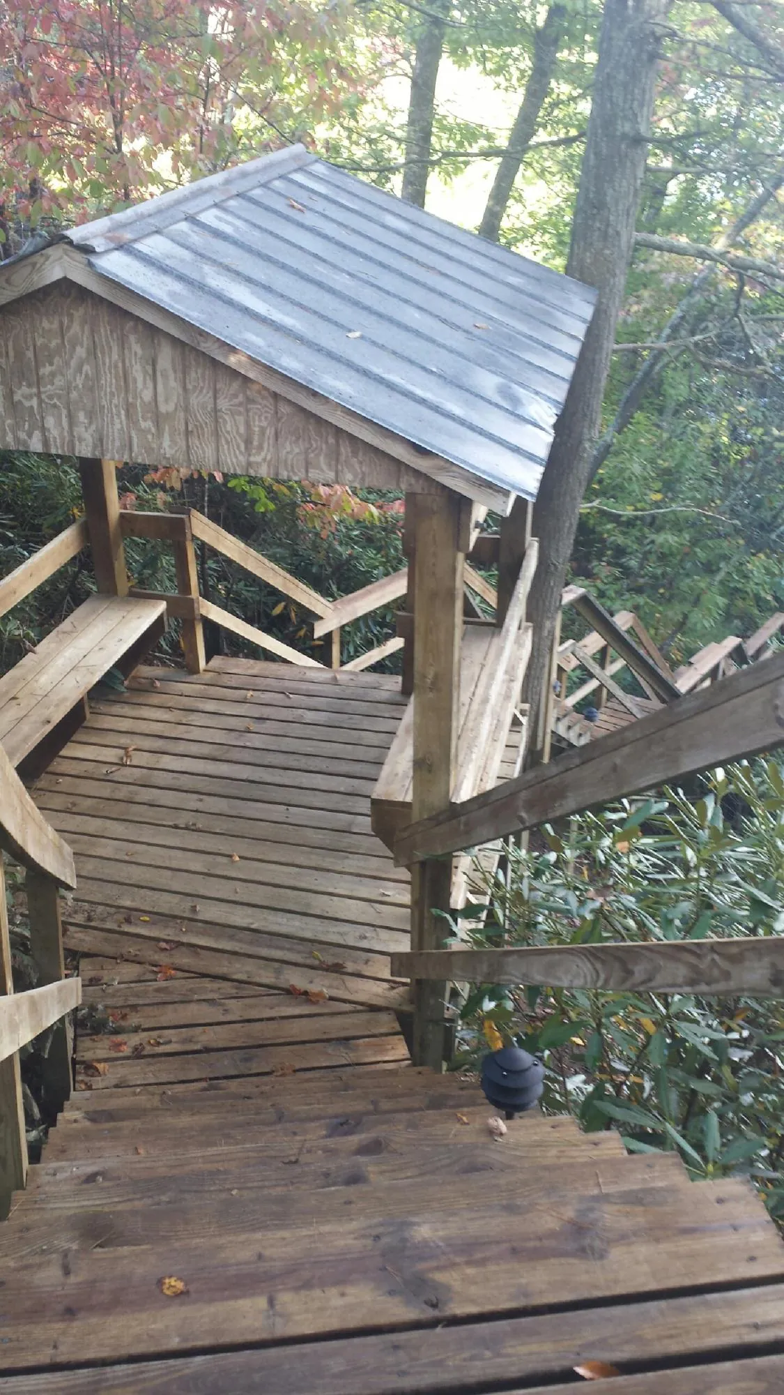 Metal roofed shelter over wooden steps on a wooded walkway — Skylight Repair & Installation work by our crew in Indian Mound