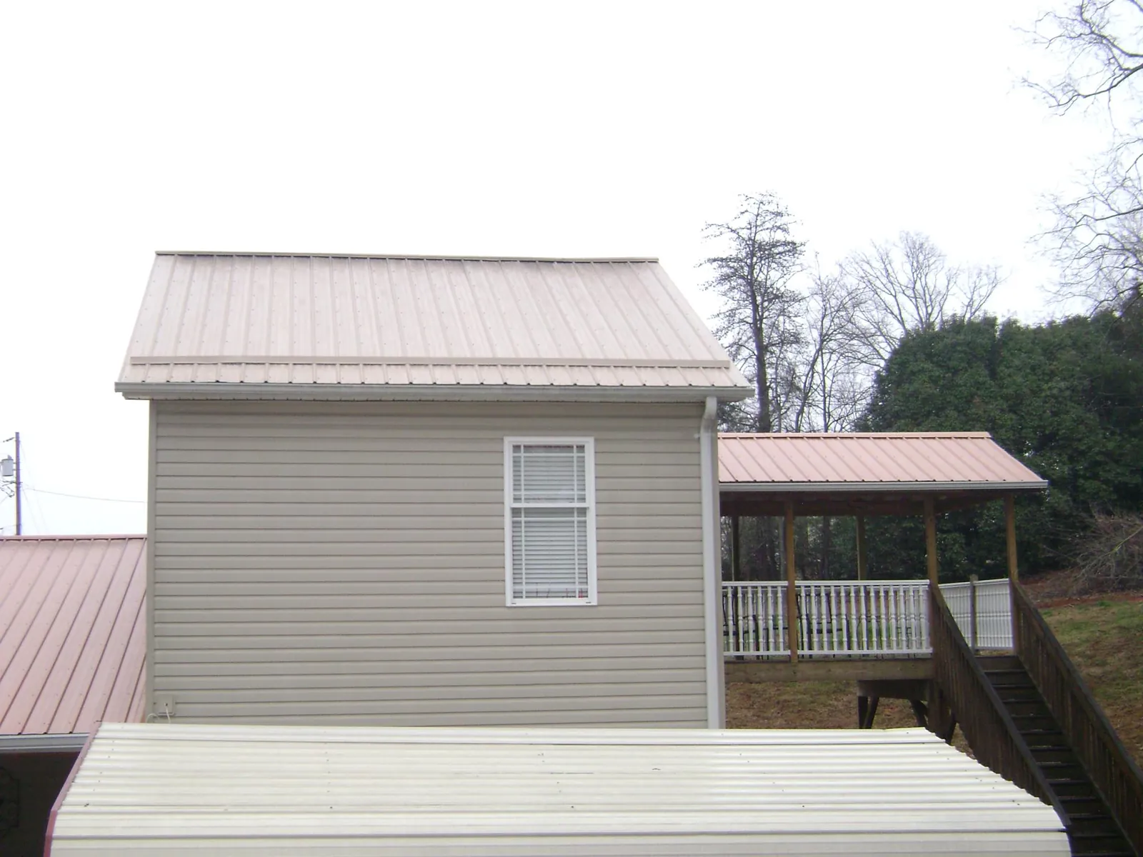 Tan metal roofs on a two story addition and attached porch, from a Roof Replacement job in Indian Mound