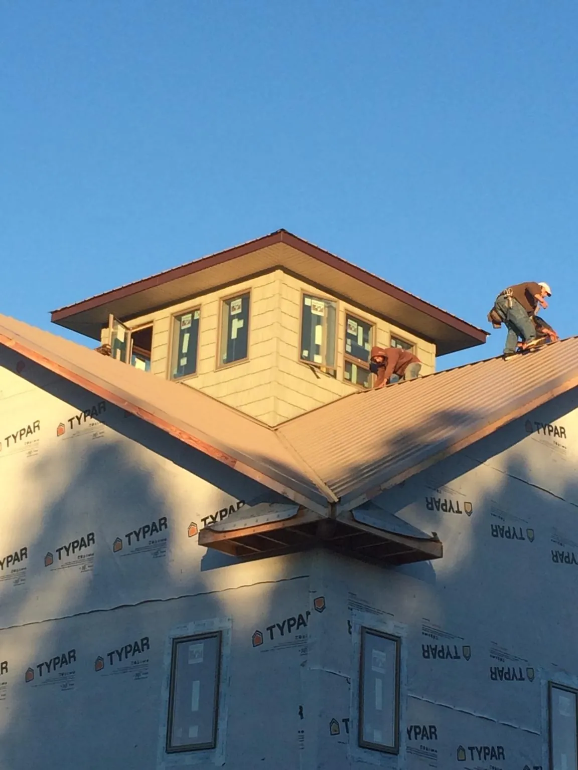 Roofers working around a rooftop cupola on a new metal roof at sunset — Roof Waterproofing in Indian Mound by Roofing Brothers